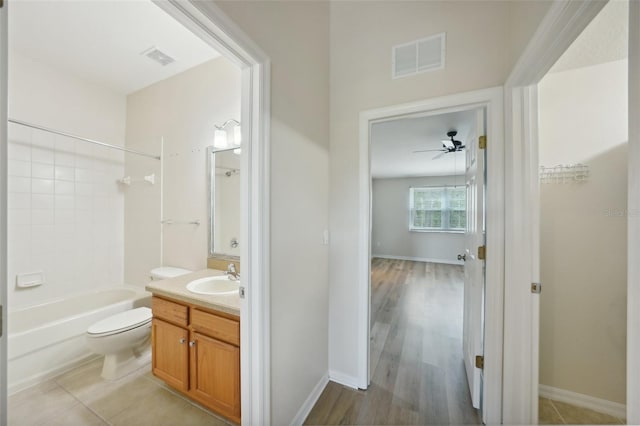 full bathroom with ceiling fan, hardwood / wood-style floors,  shower combination, toilet, and vanity