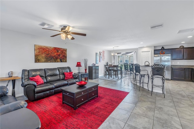 living room featuring light tile patterned floors and ceiling fan with notable chandelier