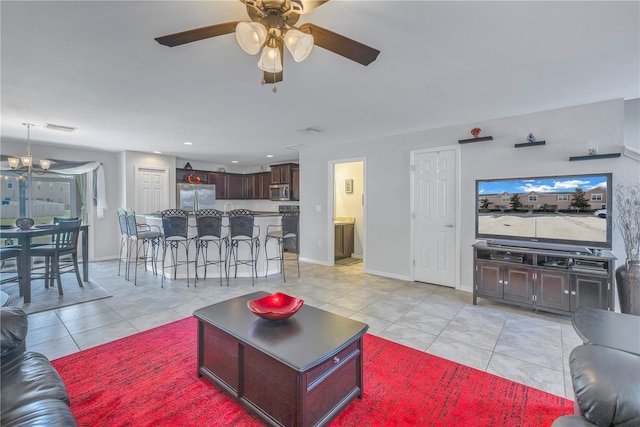 tiled living room featuring ceiling fan with notable chandelier