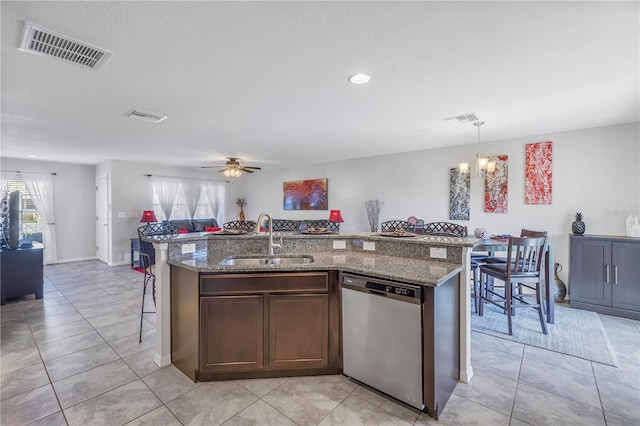 kitchen featuring stainless steel dishwasher, ceiling fan with notable chandelier, a kitchen island with sink, sink, and pendant lighting