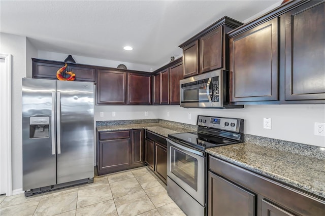 kitchen featuring dark stone countertops, light tile patterned flooring, and stainless steel appliances