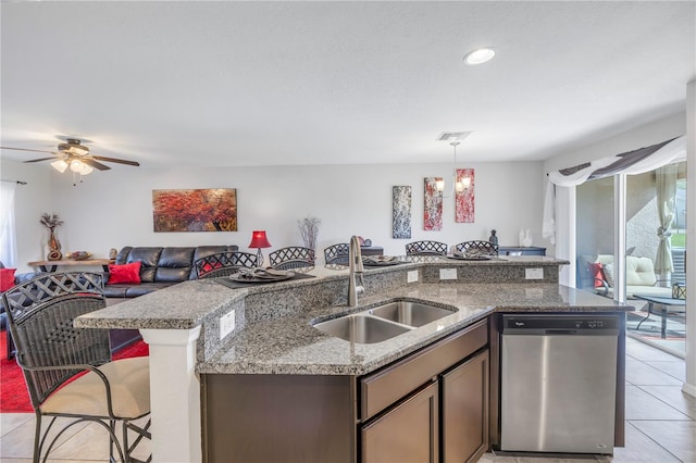 kitchen featuring dishwasher, sink, light stone countertops, decorative light fixtures, and light tile patterned flooring