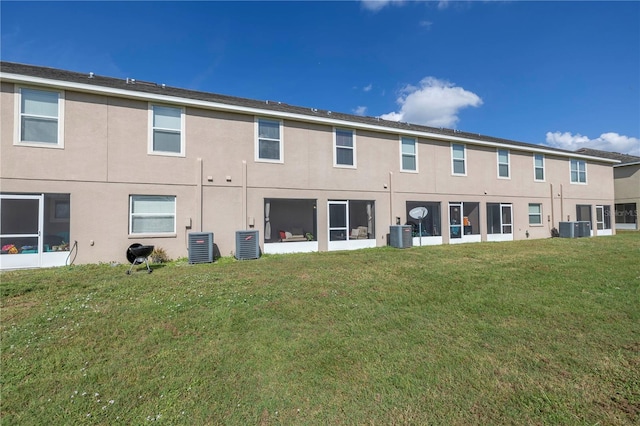 back of property featuring central AC unit and a yard