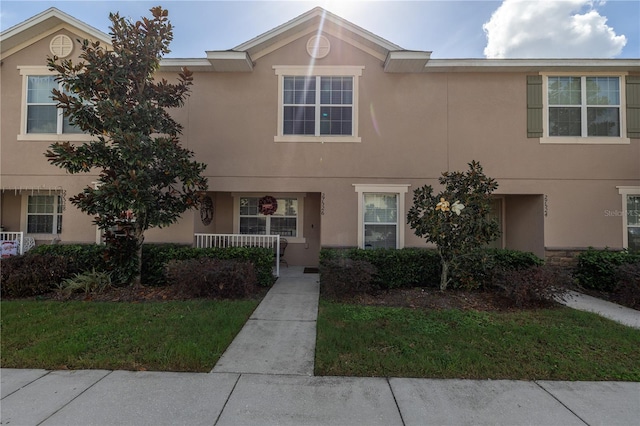 townhome / multi-family property with a porch and a front lawn