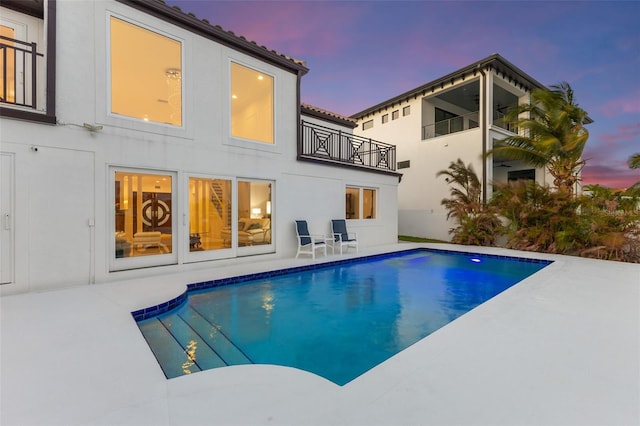 pool at dusk with a patio area