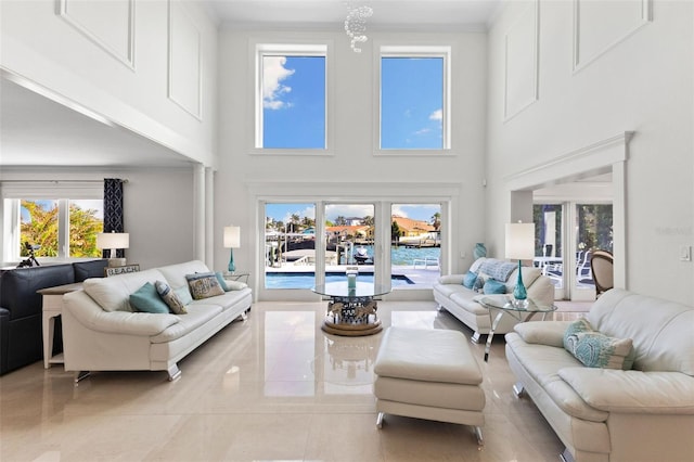 tiled living room featuring crown molding, a towering ceiling, and a healthy amount of sunlight