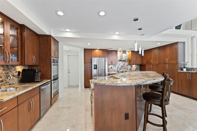 kitchen with sink, wall chimney exhaust hood, tasteful backsplash, pendant lighting, and appliances with stainless steel finishes