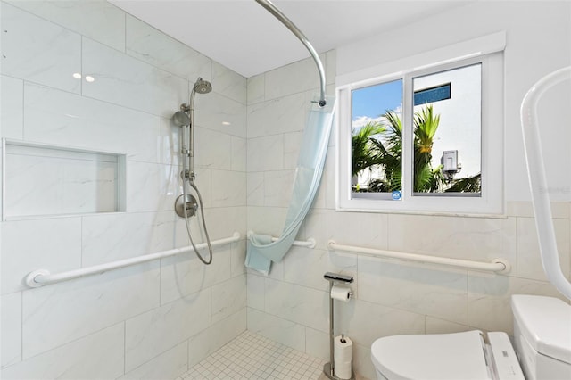 bathroom with a tile shower, tile walls, and toilet