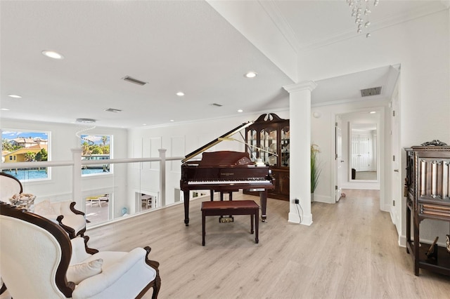 living area with ornate columns, ornamental molding, and light wood-type flooring