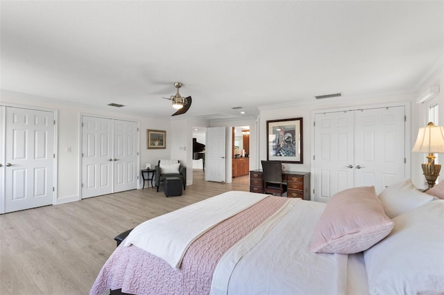 bedroom featuring multiple closets, ornamental molding, and light wood-type flooring