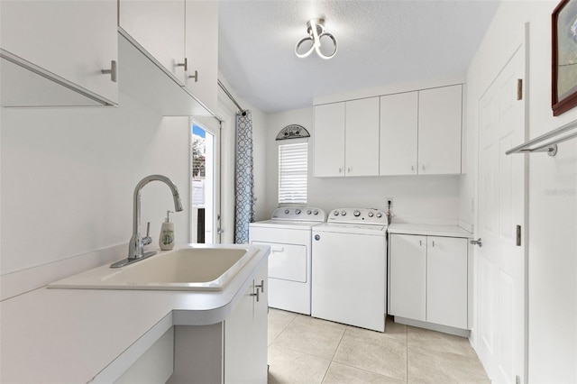 washroom with cabinets, a textured ceiling, washer and clothes dryer, sink, and light tile patterned floors