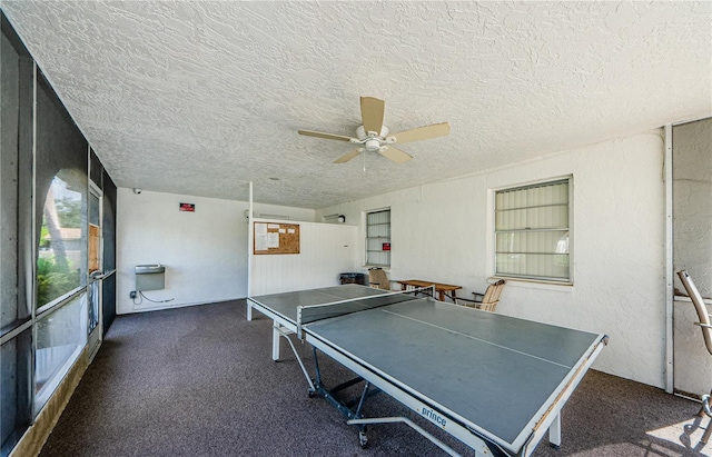 rec room featuring dark colored carpet, a textured ceiling, and ceiling fan