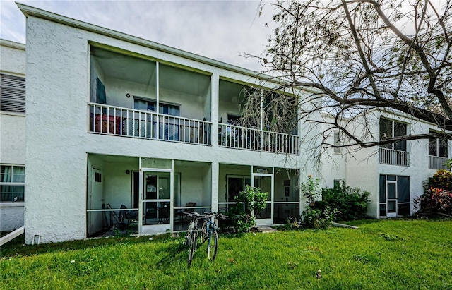 211 S Mcmullen Booth Rd Unit 189, Clearwater, FL 33759 - rear view of property featuring stucco siding, a sunroom, a balcony, and a yard