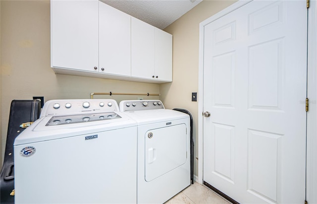 clothes washing area with cabinets, a textured ceiling, and independent washer and dryer