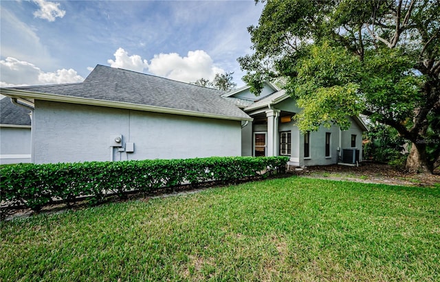 3647 Muirfield Ct, New Port Richey, FL 34655 - rear view of property with stucco siding, a lawn, a shingled roof, and central air condition unit
