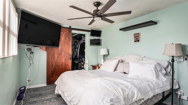 carpeted bedroom featuring a textured ceiling, a spacious closet, ceiling fan, and a closet