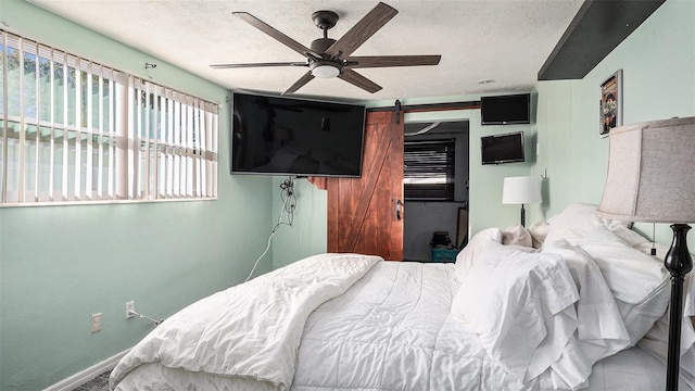 bedroom featuring a barn door, a textured ceiling, and ceiling fan