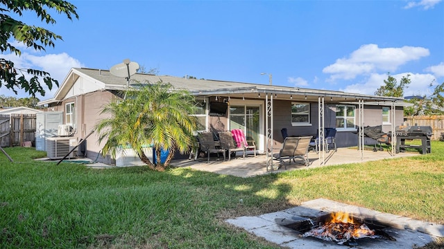 back of property with cooling unit, an outdoor fire pit, a yard, and a patio area