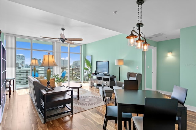 living room featuring ceiling fan, light hardwood / wood-style floors, and a wall of windows