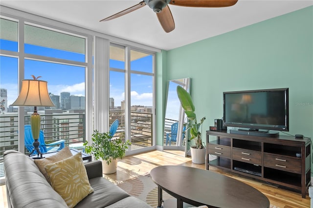 living room featuring ceiling fan, expansive windows, and light hardwood / wood-style flooring