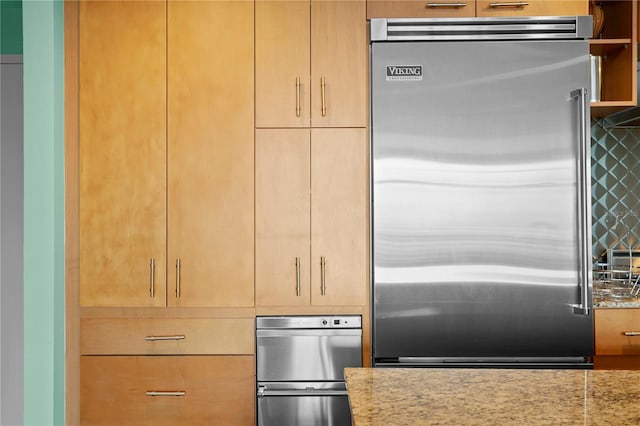 kitchen with appliances with stainless steel finishes, backsplash, and light stone counters