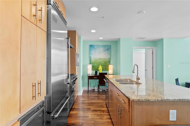 kitchen featuring light stone counters, a kitchen island with sink, sink, high quality appliances, and dark hardwood / wood-style floors