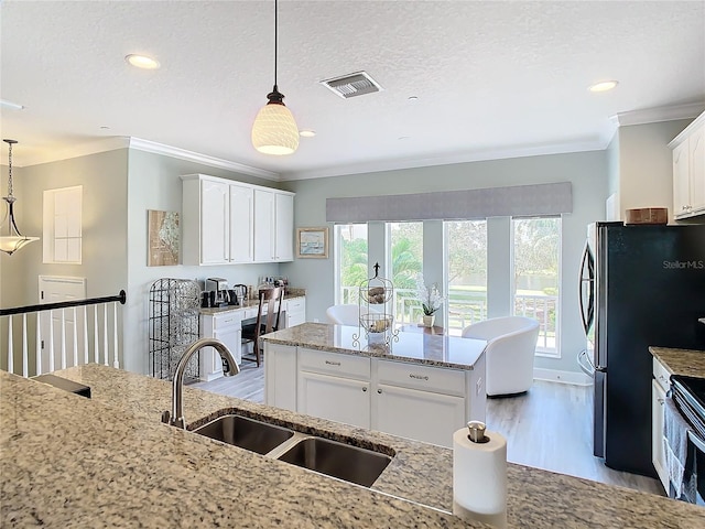 kitchen with white cabinetry, pendant lighting, sink, and light wood-type flooring