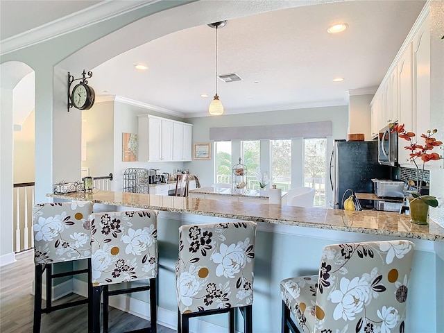 kitchen featuring light hardwood / wood-style floors, kitchen peninsula, a kitchen breakfast bar, hanging light fixtures, and white cabinets