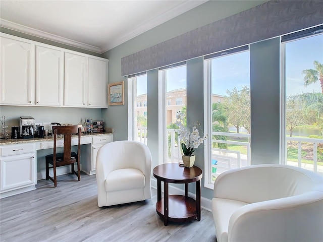 living area featuring light wood-type flooring, a water view, built in desk, and crown molding