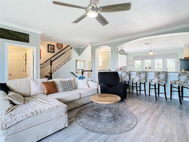 living room with ceiling fan, ornamental molding, and light hardwood / wood-style flooring