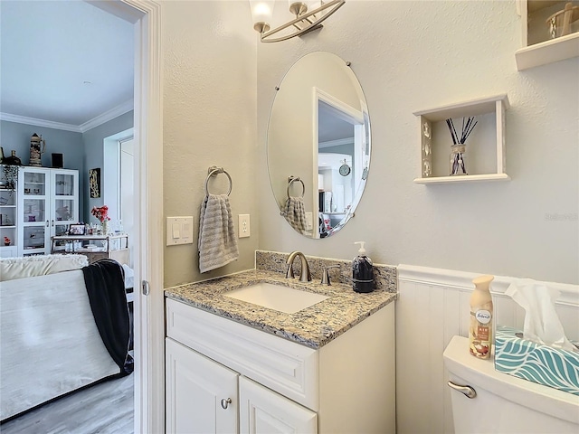 bathroom featuring toilet, hardwood / wood-style floors, vanity, and crown molding