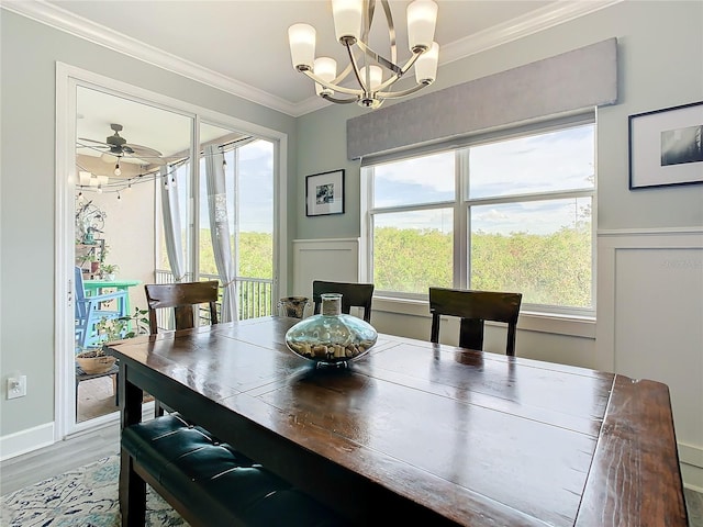 dining room with hardwood / wood-style floors, a wealth of natural light, crown molding, and ceiling fan with notable chandelier