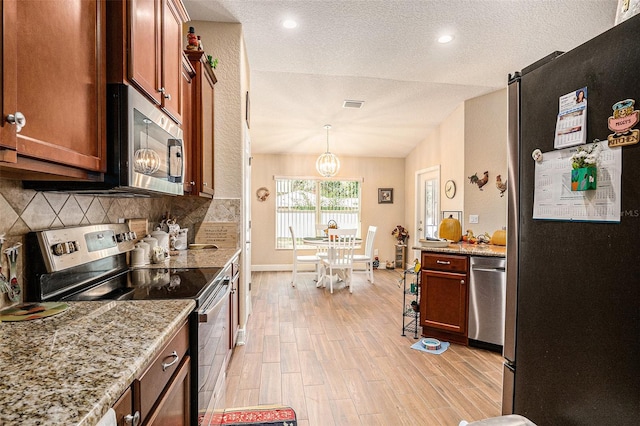 kitchen featuring decorative light fixtures, lofted ceiling, a textured ceiling, and stainless steel appliances