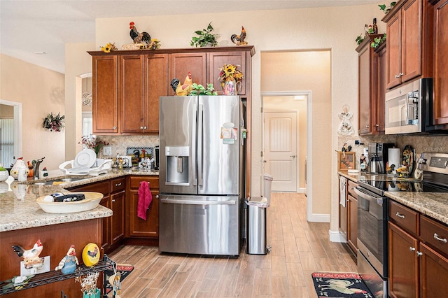 kitchen featuring light stone countertops, light hardwood / wood-style floors, backsplash, and appliances with stainless steel finishes