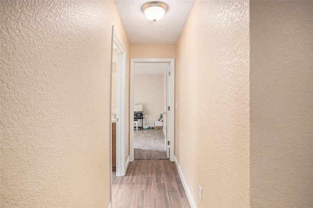 corridor with hardwood / wood-style floors and a textured ceiling