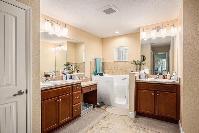 bathroom with vanity, a textured ceiling, and a bath