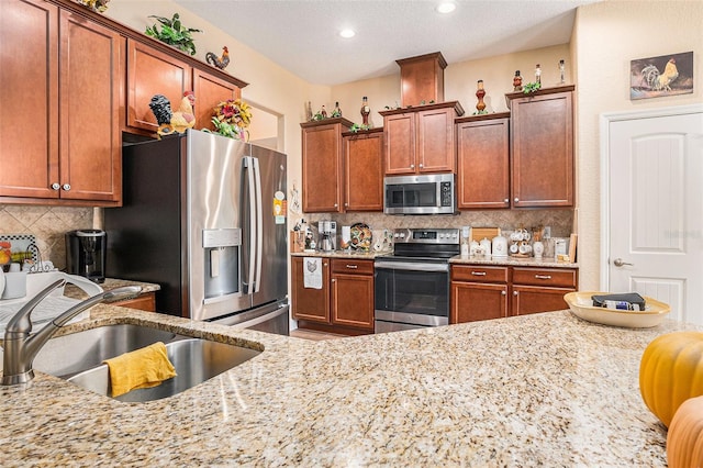 kitchen with light stone countertops, appliances with stainless steel finishes, sink, and a textured ceiling