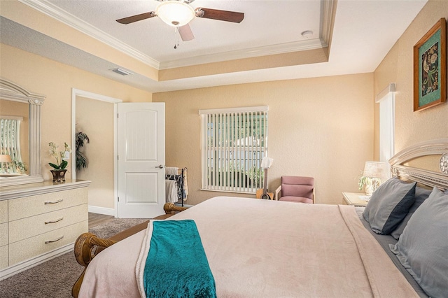 carpeted bedroom featuring ceiling fan, crown molding, and a tray ceiling