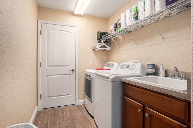 laundry area with light wood-type flooring, a textured ceiling, cabinets, sink, and washing machine and dryer