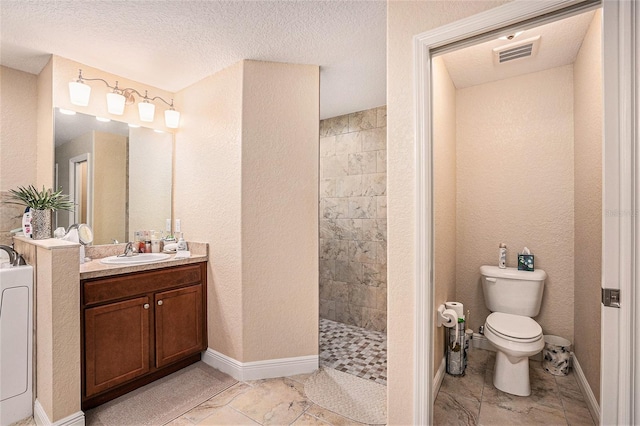 bathroom with vanity, a textured ceiling, toilet, and tiled shower