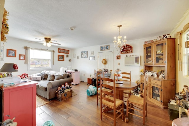 dining area featuring wood-type flooring, ceiling fan with notable chandelier, a textured ceiling, and crown molding