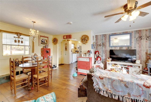 living room with wood-type flooring, ceiling fan with notable chandelier, and ornamental molding