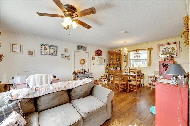 living room with wood-type flooring, ceiling fan with notable chandelier, a wall unit AC, and ornamental molding