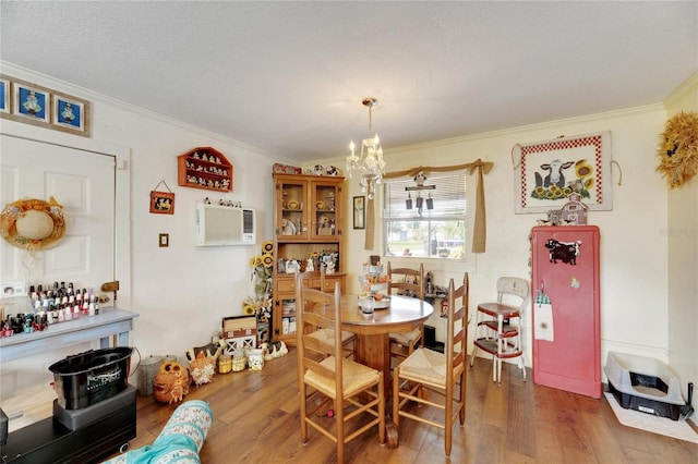 dining area with hardwood / wood-style floors, a notable chandelier, crown molding, and a wall mounted AC