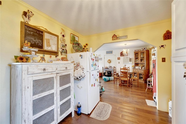 kitchen with a chandelier, wood-type flooring, white fridge, and ornamental molding