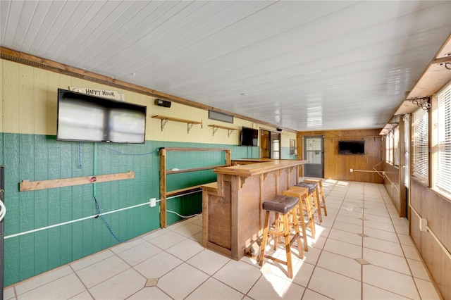 kitchen with butcher block countertops, light tile patterned floors, a breakfast bar area, and wooden walls