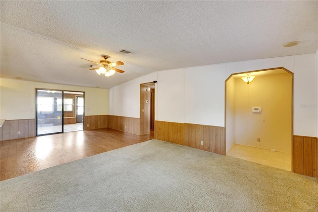 spare room with a textured ceiling, light hardwood / wood-style floors, vaulted ceiling, and ceiling fan