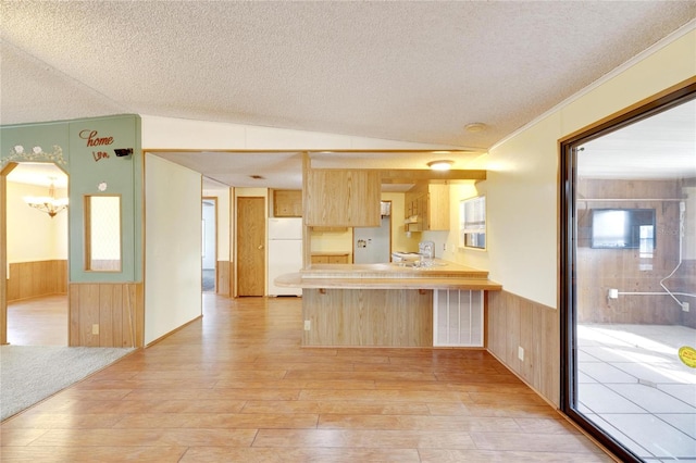 kitchen featuring light brown cabinets, white refrigerator, kitchen peninsula, hardwood / wood-style floors, and vaulted ceiling