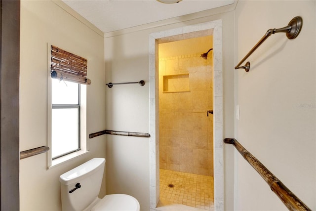 bathroom with a healthy amount of sunlight, toilet, and tiled shower