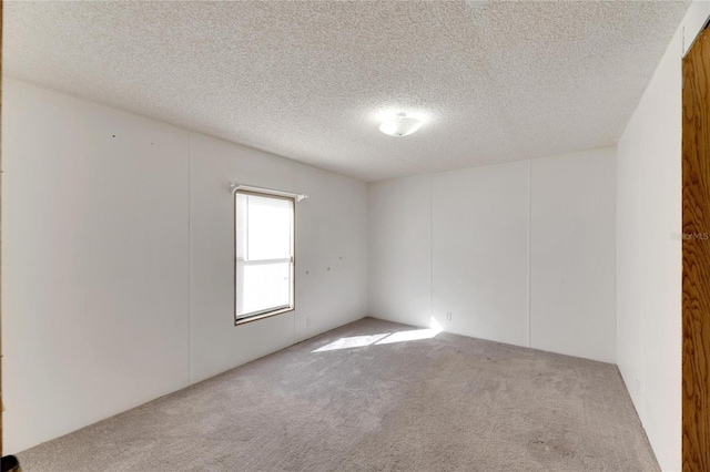 unfurnished room featuring light colored carpet and a textured ceiling